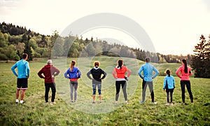 Rear view of large group of multi generation sport people standing in nature.