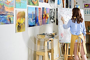 rear view of left-handed female artist painting on canvas