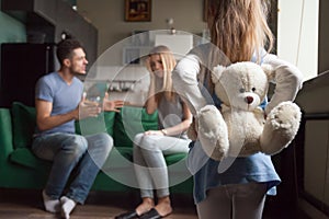 Rear view little girl holding toy while parents fighting