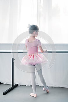 rear view of little kid in pink tutu practicing ballet in ballet