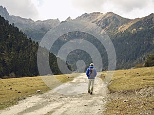 Rear view of lone asian hiker walking on dirt road