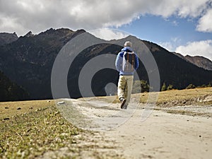 Rear view of lone asian hiker walking on dirt road