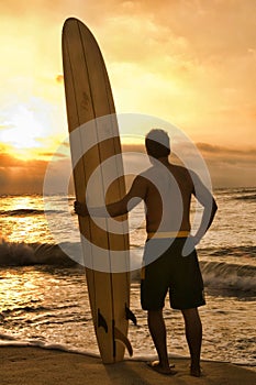 Rear view of Longboard Surfer Enjoying Sunset on Beach