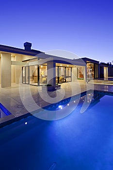 Rear view of luxury villa at night time with swimming pool