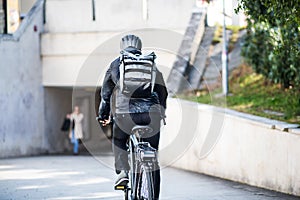 A rear view of male bicycle courier delivering packages in city. Copy space.