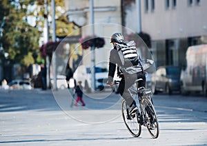 A rear view of male bicycle courier delivering packages in city. Copy space.