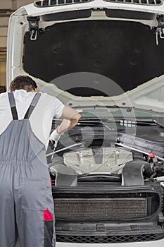 Rear view of male engineer repairing car in automobile repair shop