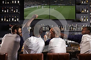 Rear View Of Male Friends Watching Game In Sports Bar