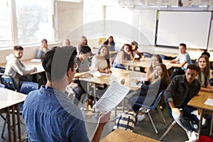 Rear View Of Male High School Teacher Standing At Front Of Class Teaching Lesson