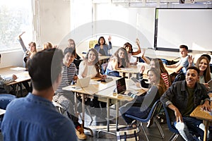 Rear View Of Male High School Teacher Standing At Front Of Class Teaching Lesson photo