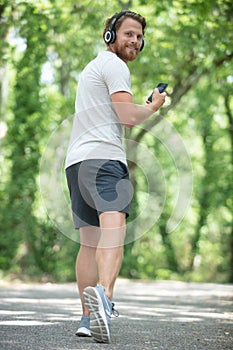 rear view male jogger wearing headphones