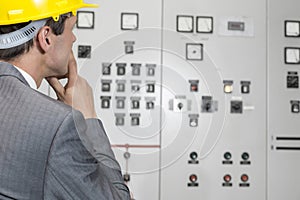 Rear view of male supervisor examining control room in industry