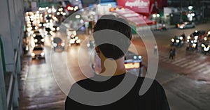 Rear view male tourist looking at cityscape night traffic at downtown. Urban street at night time. Back view millennial