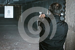 rear view of man aiming gun at target