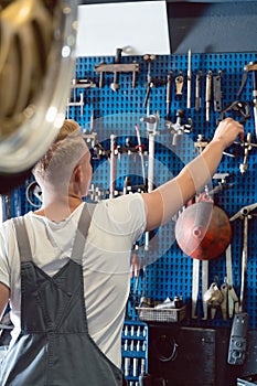 Rear view of a man choosing an useful tool during work in a repair shop