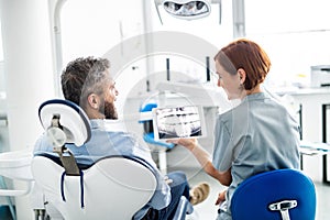 Rear view of man and dentist in dental surgery, annual check-up.