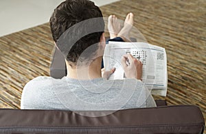 Rear view Of Man Doing Crossword Puzzle In Newspaper