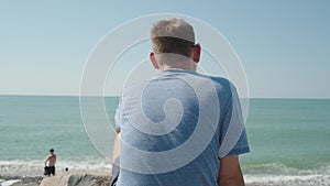 Rear view of man with earphones on beach listening music. Serenity, contemplation, inspiration, day dreaming, relaxation