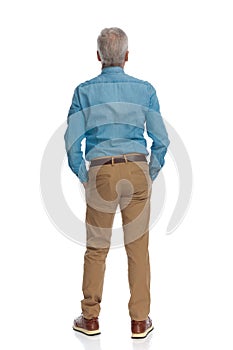 Rear view of man with grizzled hair wearing denim shirt and chino pants