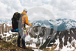 Rear view of man hiker with backpack standing on top of the mountain enjoying the view