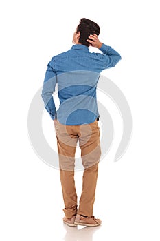 Rear view of man looking to side while scratching head