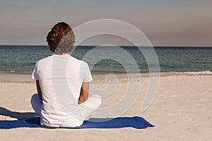 Rear view of man meditating at beach