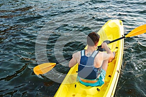 Rear view of man paddling kayak