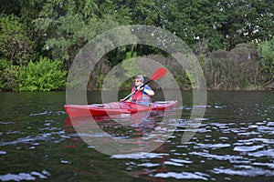 Rear view of man paddling kayak in lake with woman in background. Couple kayaking in lake on a sunny day.