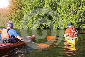 Rear view of man paddling kayak in lake with woman in background. Couple kayaking in lake on a sunny day.