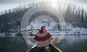 Rear view of man paddling on winter canoe ride