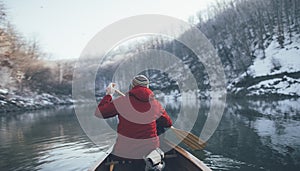 Rear view of man paddling on winter canoe ride