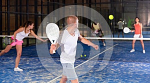 Rear view of man playing doubles paddle tennis on indoor court