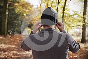 Rear View Of Man Putting In Earphones Before Autumn Run