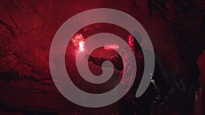 Rear view of a man with red burning signal flare going towards light to to get out of the cave. Stock footage