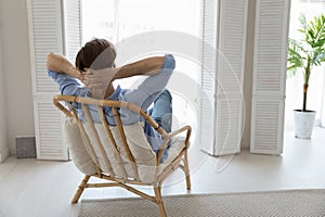 Rear view man relaxing on chair daydreams looks into distance