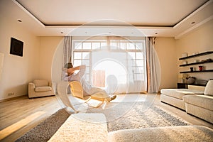 Rear view of man relaxing on modern chair at home