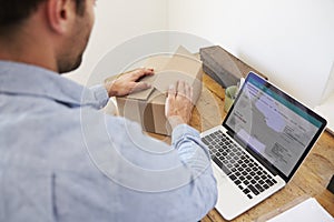 Rear View Of Man Running Business From Home Dispatching Goods