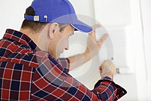 rear view man screwing object to wall