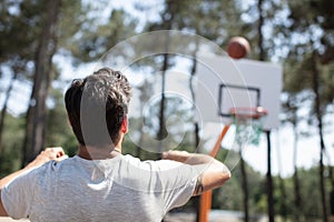 rear view man shooting basketballs