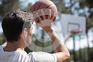 rear view man shooting hoops on basketball court