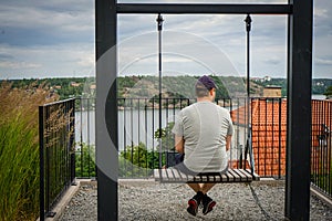 Rear view of man sitting on swing against sky