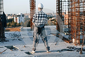 Rear view. Man is standing on the construction site at daytime