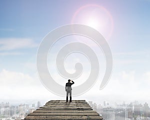 Rear view man standing gazing on wooden bridge