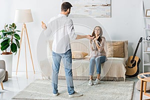 rear view of man standing with glasses and bottle of champagne while his girlfriend