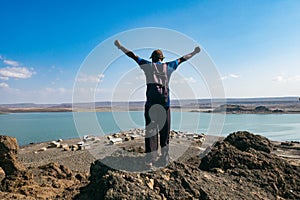 Rear view of a tourist against the background of El Molo village at the shores of Lake Turkana in Loiyangalani, Kenya