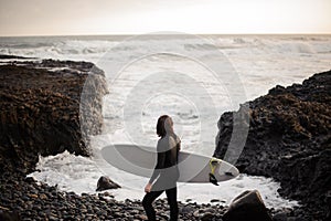 Rear view man standing with a white surf in his hands on the beach