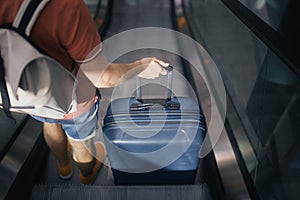 Rear view of man with suitcase and backpack on escalator