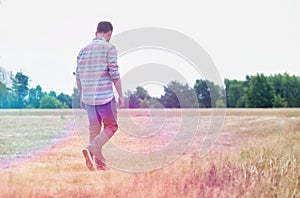 Rear view of Man walking alone in field