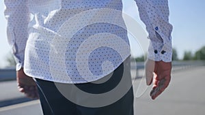 Rear view of a man walking along Ðµmpty the road. Close up shot.