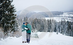 Rear view of mature couple on walk outdoors in winter nature, Tatra mountains Slovakia.